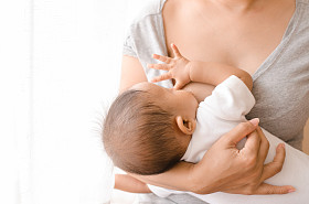 她刚出生的婴儿在窗口旁边的母亲母乳喂养