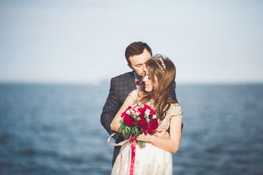 刚结婚的婚礼夫妇海滩上散步，在日落时分