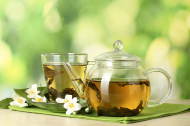 綠茶與茉莉花在杯子和綠色背景上的木桌上的茶壺