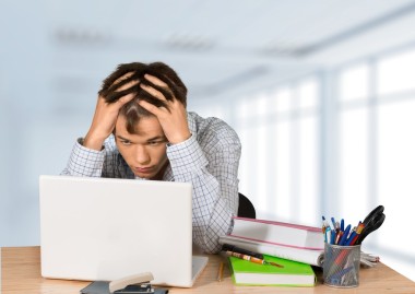 男學(xué)生坐在餐桌旁與筆記本電腦和書籍