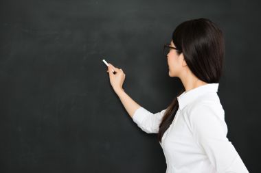 一个好的亚洲老师写在黑板上用粉笔 一个好的亚洲老师写在黑板上用粉笔