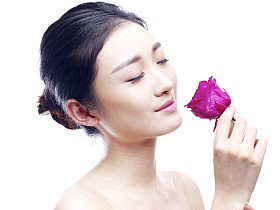 年轻的亚洲女人享受的红玫瑰的芳香