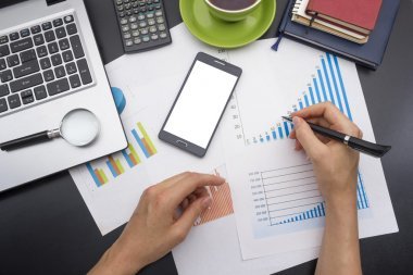 年轻女子支票帐户的特写。办公室桌子与用品顶视图