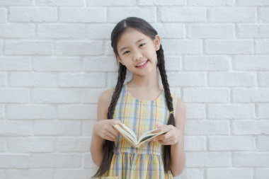 讀故事書白色磚墻上的亞洲女孩