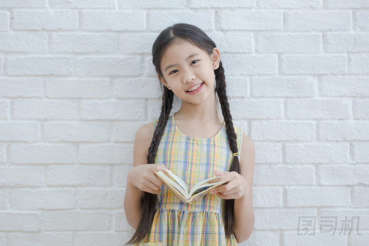 讀故事書白色磚墻上的亞洲女孩