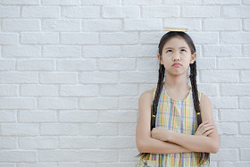 亚洲女孩读故事书白色砖墙上的滑稽的动作肖像