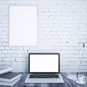 创意设计师桌面与空白白色笔记本电脑，书籍，咖啡杯，台灯和空白相框砖墙背景。模拟，3d 渲染