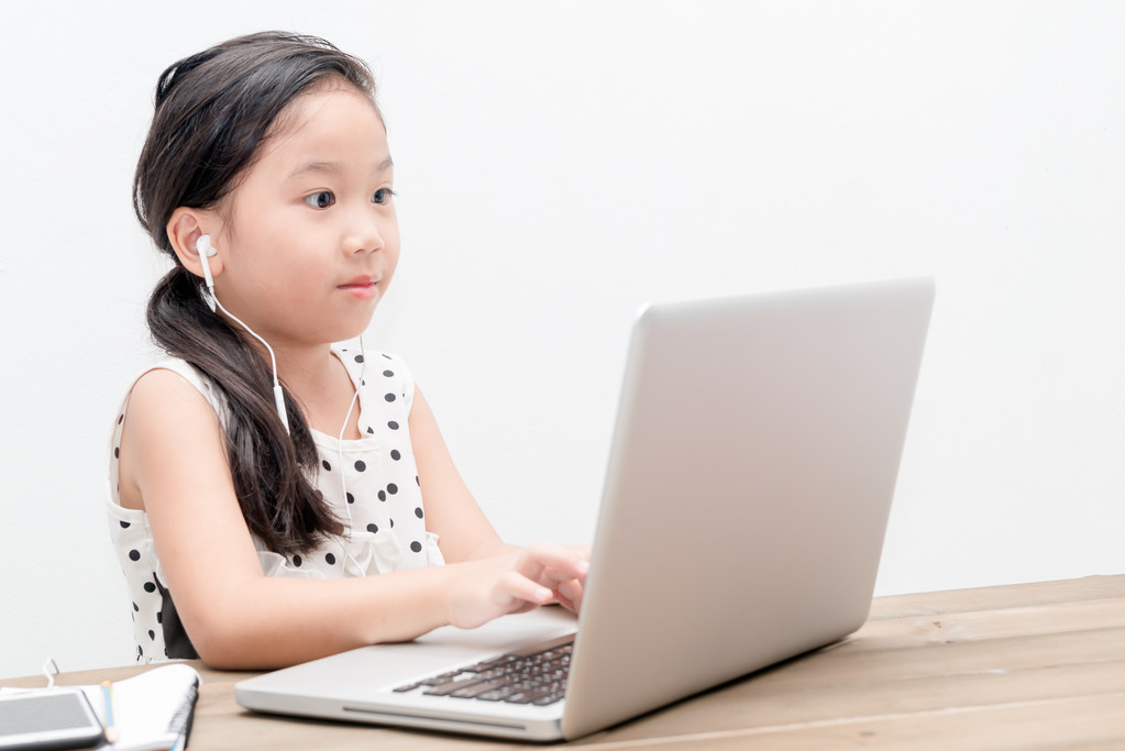 可爱的女生女孩与桌上的笔记本电脑电脑