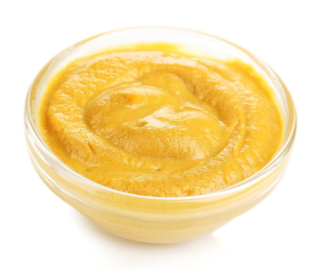 在孤立在白色的玻璃碗芥末照片 在孤立在白色的玻璃碗芥末照片