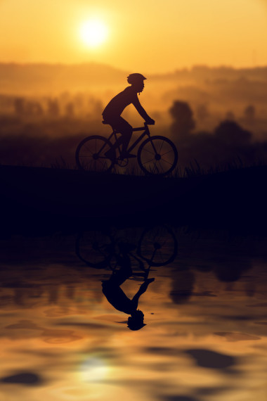 一個(gè)人對(duì)封山育林自行車(chē)，日落的輪廓