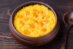 小米在仿古木制背景上的粘土碗南瓜粥