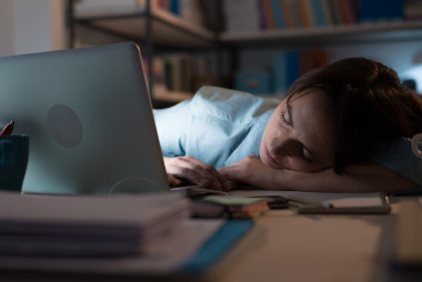疲憊的女子睡附近筆記本電腦照片