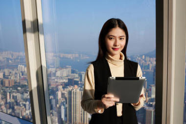 一名年輕的亞洲女性拿著便攜式數碼平板電腦