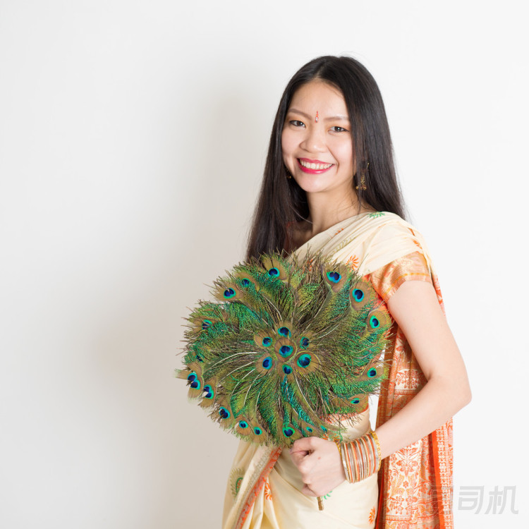 年輕女孩穿著印度紗麗連衣裙拿著孔雀羽毛扇