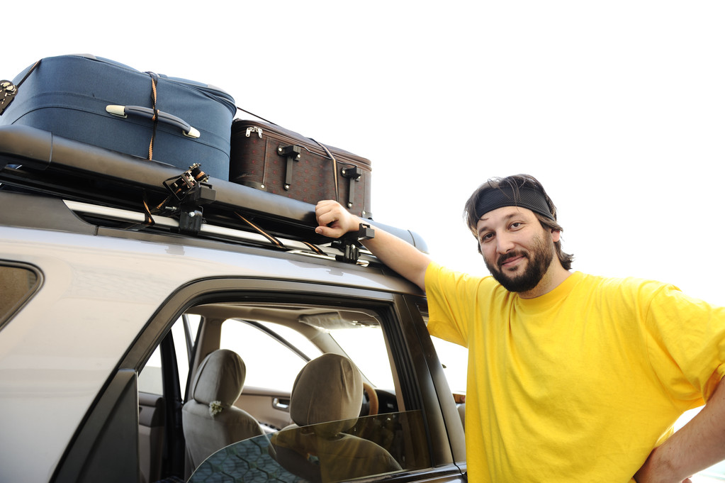 年轻男子制备的旅行,车顶上的行李 年轻男子制备的旅行,车顶上的行李