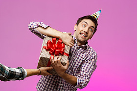 男人撕掉生日礼物在盒子在紫色背景