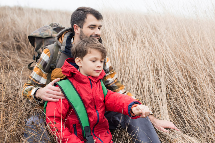 父親帶兒子坐在草照片