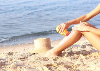 年輕女子在大海背景上使用防曬霜