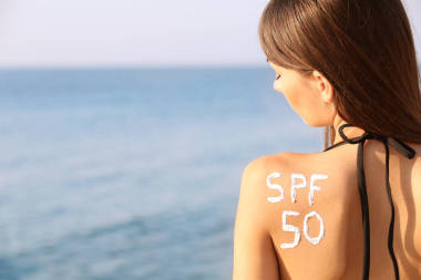 防曬霜在背上，海面背景的年輕女子