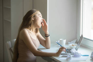 有魅力的女人，打哈欠在筆記本電腦的側(cè)面肖像