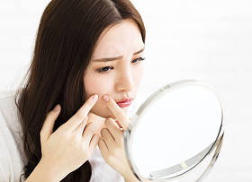 年轻女人挤她的粉刺在镜子前图片