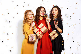 与礼物的圣诞老人帽子三个快乐年轻妇女的肖像