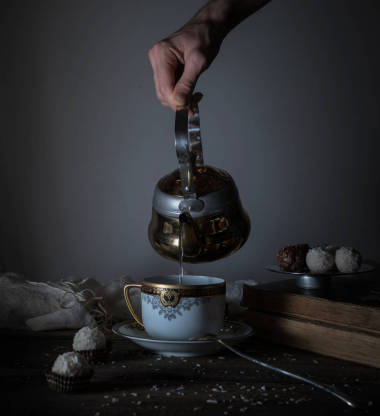 静物。手倒在透明杯中的茶。黑暗的背景复古