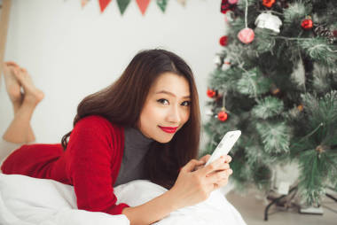 在圣誕節(jié)上使用移動電話的亞洲女人