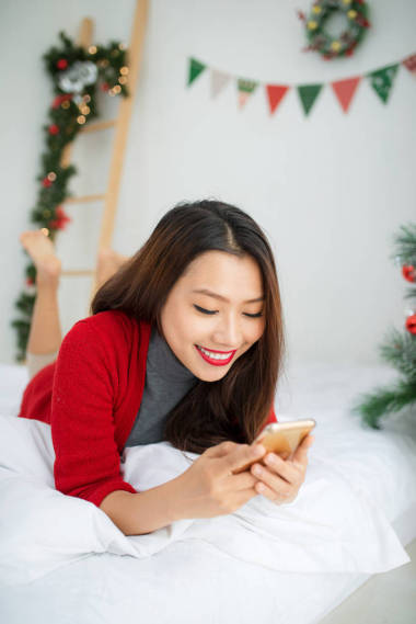 年輕微笑亞洲女人正在使用移動(dòng)電話。圣誕節(jié)和 N
