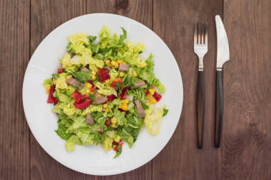 從牛舌、 大白菜、 辣椒、 玉米、 歐芹和羅勒沙拉。木制的背景。頂視圖