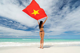 年轻漂亮的女孩，在黑色的比基尼泳装举行越南的国旗