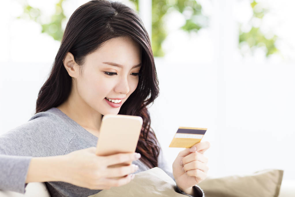 年轻漂亮的女人，与信用卡和智能手机