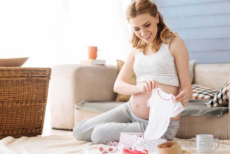 懷孕的女人看著新生嬰兒的衣服