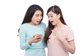 两个年轻女孩使用智能手机。微笑的年轻女性朋友 
