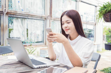 年輕快樂(lè)休閑亞洲女人對(duì)她的筆記本電腦公司使用技術(shù)