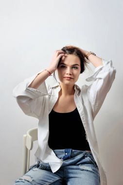 牛仔褲和襯衫舉行手頭發(fā)在椅子上有吸引力的時尚模特