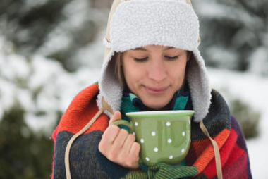 美丽的女人放松，快乐的年轻女子与一杯热茶在冬季散步