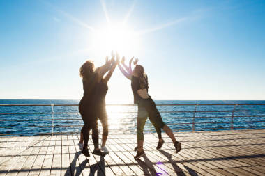嬉戲的女孩給高五國海邊日出時的剪影