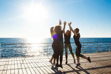 嬉戲的女孩給高五國海邊日出時的剪影