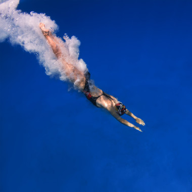 專業(yè)女性游泳后以藍色水中的空氣氣泡徑跳