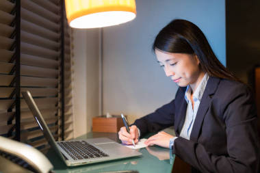 在用筆記本電腦的紙張上書寫的女商人