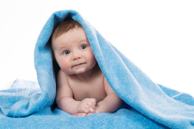 剛出生的嬰兒躺和微笑在藍(lán)色的毛巾