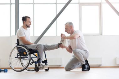老年骨科醫(yī)生和殘疾病人在健身房里一起工作