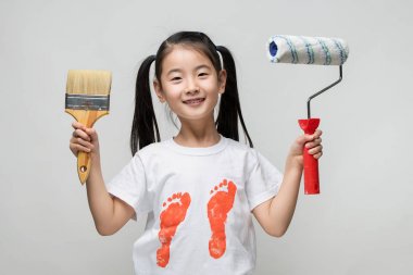 可爱的亚洲女孩抱着画笔和颜料的滚子