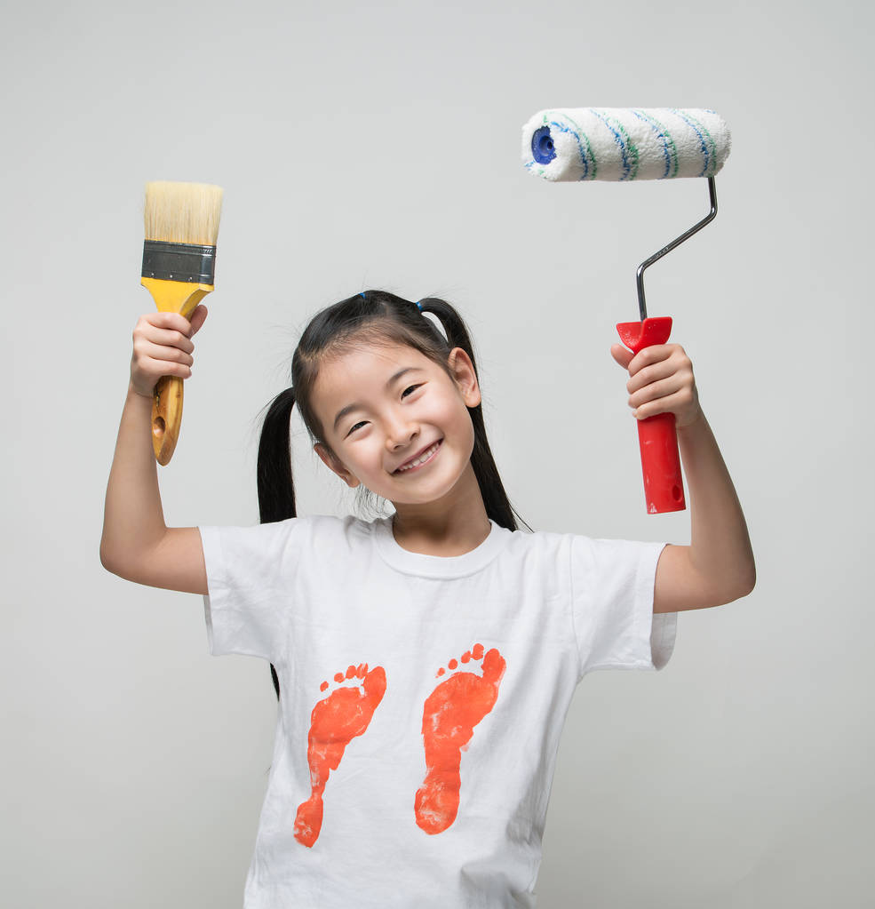 可爱的亚洲女孩抱着画笔和颜料的滚子 可爱的亚洲女孩抱着画笔和颜料的滚子