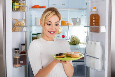 年輕女人吃甜甜圈從板