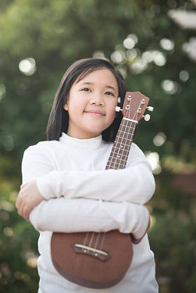 亚洲女孩玩户外人像的四弦琴