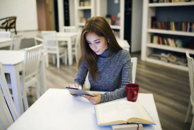 集中的女孩，通過數(shù)字設(shè)備連接到無線大學(xué)圖書館無線區(qū)域的快速 5 g
