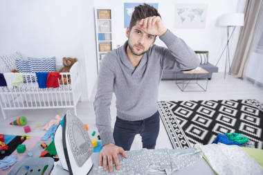 筋疲力盡的父親熨燙嬰兒衣服