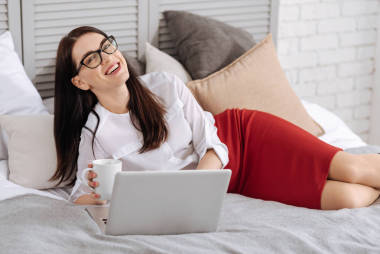 女人拿着杯子和笔记本电脑上工作